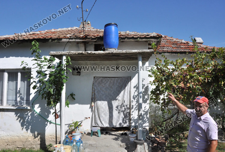 Сали Емугла посочва бидона, който е свързан с маркуч за пералнята