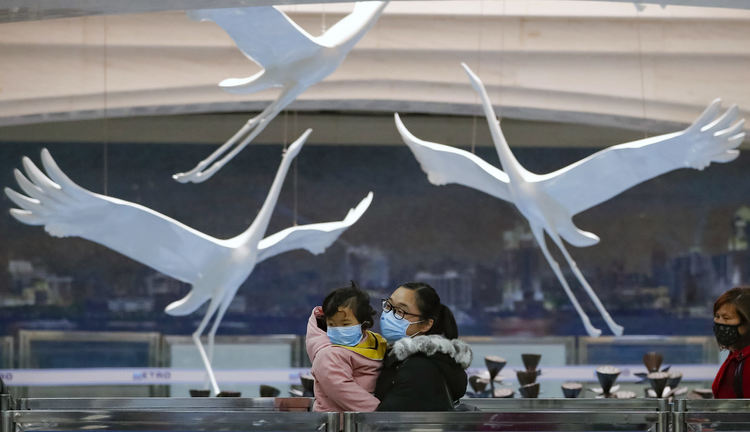 Пътничка държи детето си за проверка, преди да влезе в метростанцията на жп гара Ханку в Ухан, централната китайска провинция Хубей, на 28 март 2020 г.