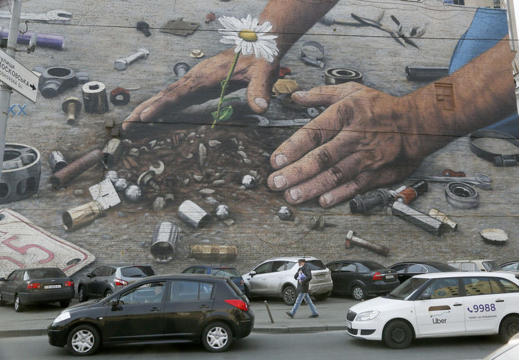 Минувач с маска преминава край графити за околната среда на стена в Киев във вторник, 31 март 2020 г. Украйна е под карантина от 12 март.