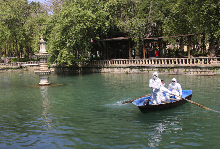 Общински работници, носещи защитни маски за лице и костюми като превантивна мярка срещу разпространението на коронавируса, на лодка, хранят рибата в емблематичното езеро Баликлигьол в град Санлиурфа, Югоизточна Турция, сряда, 8 април 2020 г. Това е един от символите на града, редовно посещавани от хиляди хора всеки ден. Мястото е празно заради мерките срещу коронавируса, а служителите хранят риби, гълъби и бездомни кучета и котки около центъра на града, известен в еврейските и ислямските легенди като мястото, където крал Нимрод хвърлил пророк Авраам в огъня.