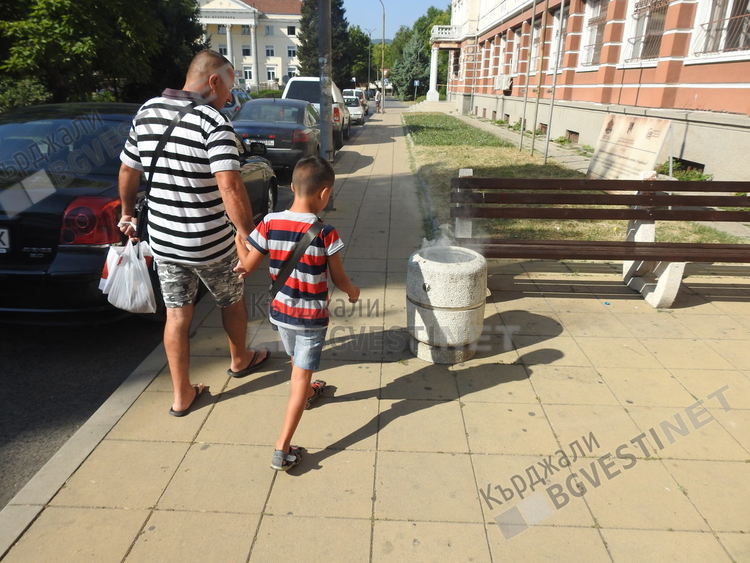 Родител дава пример на детето си-подминава безучастно подпалено кошче за боклук в центъра