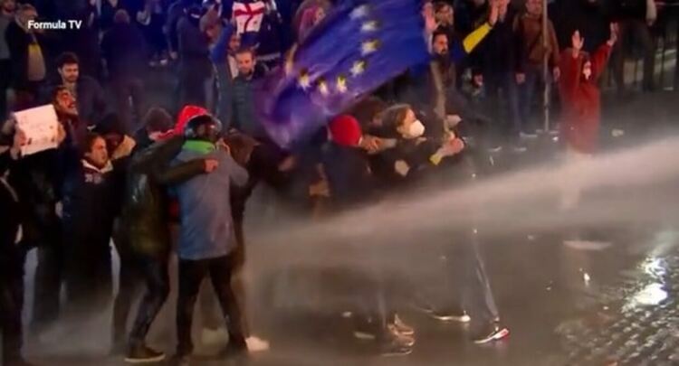 Грузия, 2023 г. Жена с европейския флаг срещу водните оръдия и руския закон