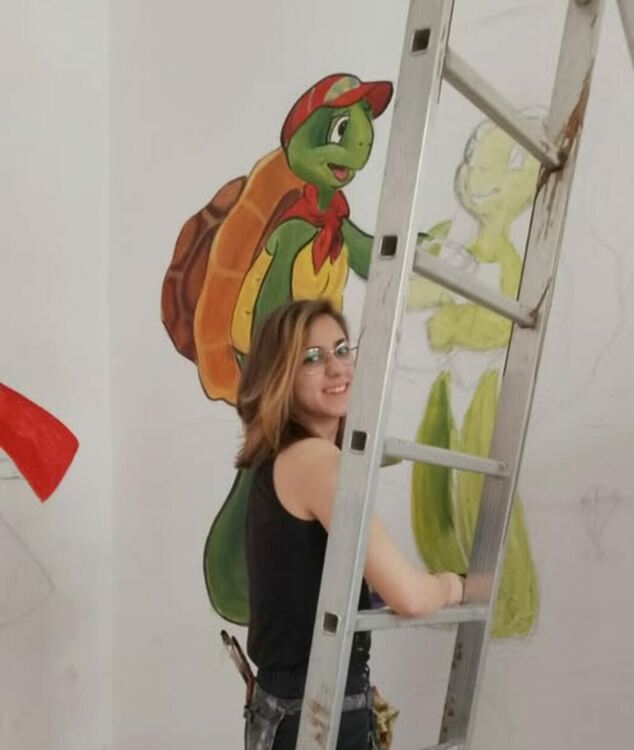 Младата художничка Ивайла Василева рисува приказни герои в детския отдел на Регионалната библиотека